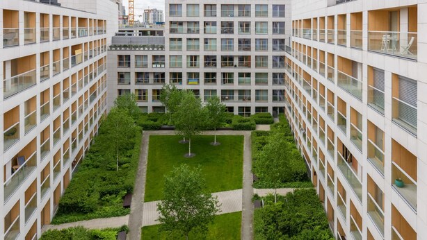 A multi-story building with a central courtyard featuring trees and pathways.