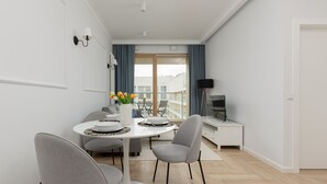 A modern dining area with a round table, grey chairs, and a vase of flowers.