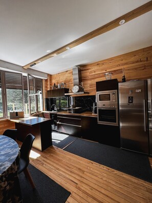 A modern kitchen with wooden accents, a built-in oven, and a refrigerator. - Maison à la Montagne (Saint-Nicolas-la-Chapelle)