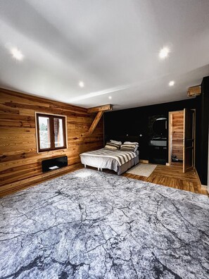 A bedroom with wooden walls, a bed, a TV, and a window. - Maison à la Montagne (Saint-Nicolas-la-Chapelle)