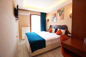 A hotel room with a bed, a desk, a television mounted on the wall, and a window with curtains. - Casta Diva Urla (Urla)
