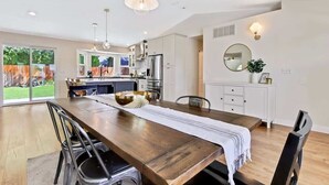 A modern kitchen with white cabinets, stainless steel appliances, and a dining area with a wooden table and chairs.
