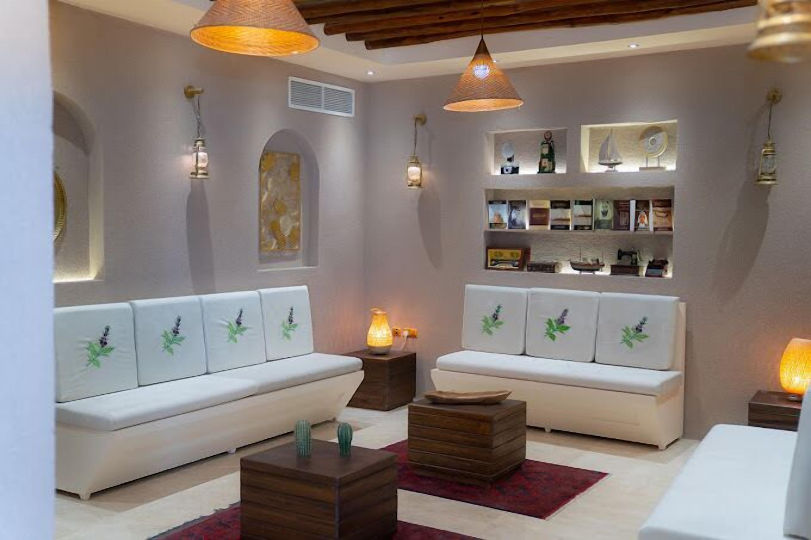 A modern living room with white sofas, wooden side tables, and pendant lighting.
