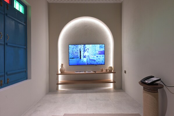 A modern interior with a TV mounted on a wall, a wooden console table, and a telephone on a stand. - NOZOL ALRAYAHEEN  (Khor Fakkan)