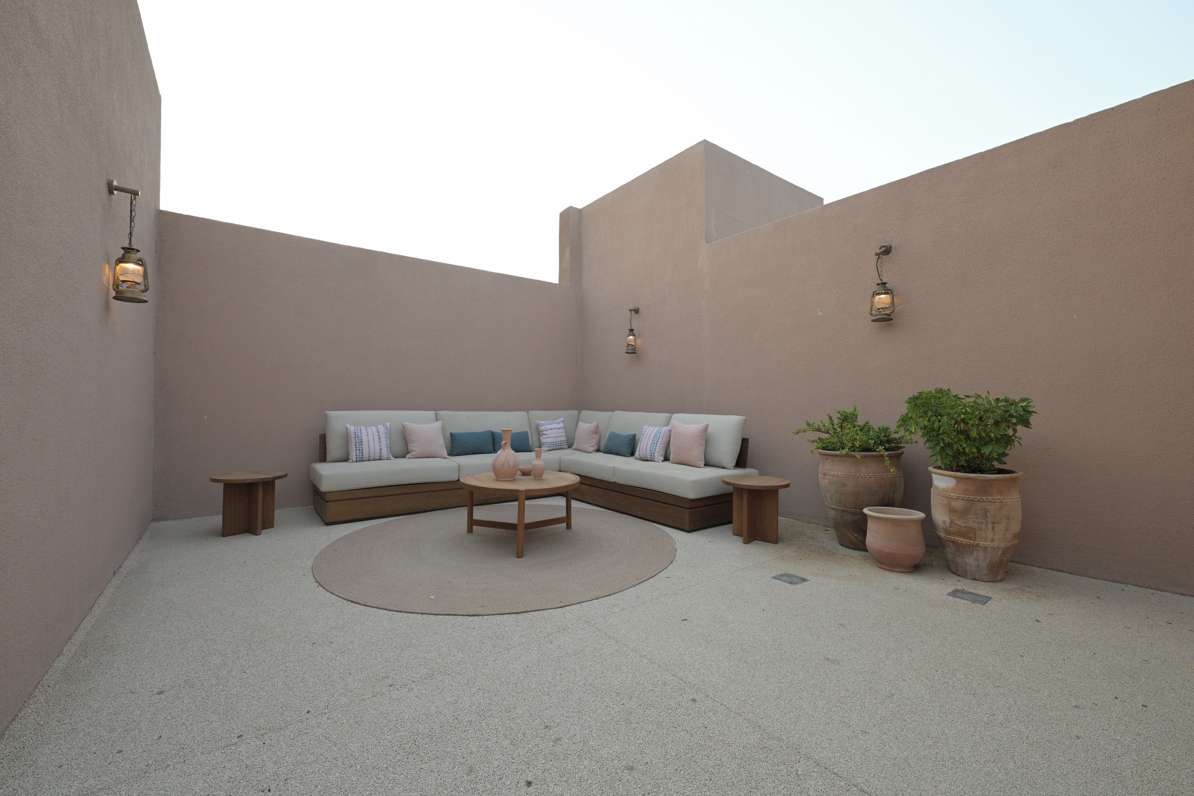 A cozy outdoor seating area with a sofa, coffee table, and potted plants.