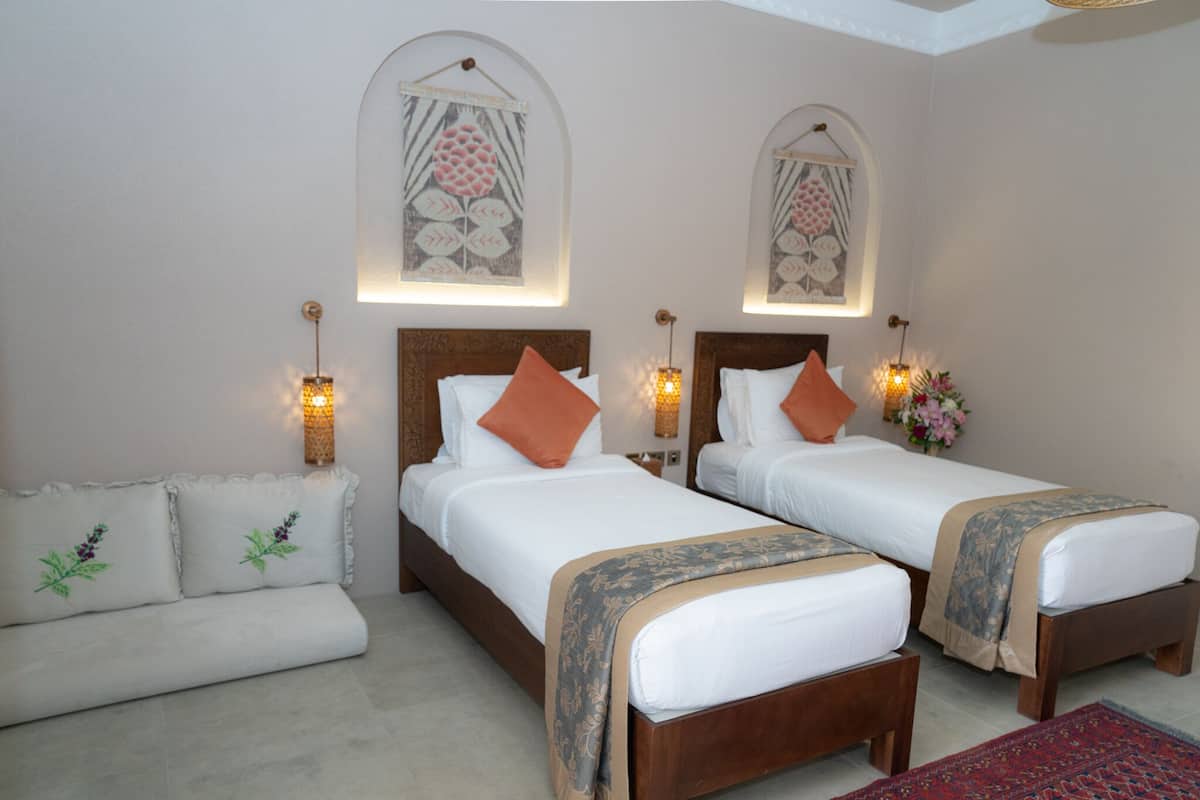 A hotel room with two beds, a sofa, and decorative wall art.