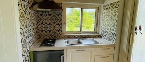 Una cocina pequeña con ventana, un lavamanos, una estufa y un refrigerador.