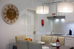 Un coin repas agrémenté d’une horloge murale en bois, d’une table mise avec des assiettes, des verres et une bouteille de vin.