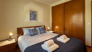 Ein Schlafzimmer mit einem Bett, zwei Nachttischen, einem Schrank und einer Wand mit einem gerahmten Kunstwerk.