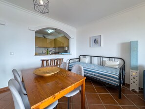A compact living space with a dining area, kitchenette, and a bed. - Sunset Apartment by ACasaDasCasas (Ericeira)