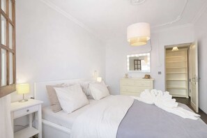 Une chambre à coucher comprenant un lit, des tables de chevet, une commode, un miroir et une armoire.