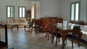 Ein geräumiges Wohnzimmer mit einer Couch, einem Esstisch, Stühlen und einem Bücherregal.