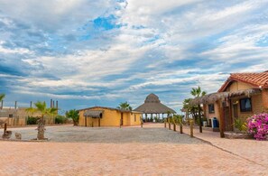 Ein Resort mit strohgedeckten Hütten, Palmen und einem gepflasterten Innenhof.