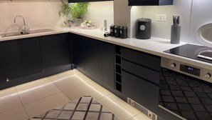 A modern kitchen with dark cabinetry, a white countertop, a built-in stove, and a small plant on the shelf. - 2 Bed Cosy Cottage, Bawtry - High End Accommodation (Bawtry)
