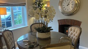 A dining area with a round table, chairs, a clock, and a fireplace. - 2 Bed Cosy Cottage, Bawtry - High End Accommodation (Bawtry)