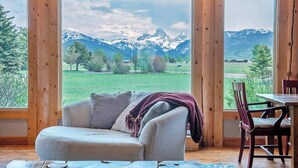 Una habitación acogedora con un ventanal que ofrece vistas a la montaña, un sofá cómodo y un comedor.