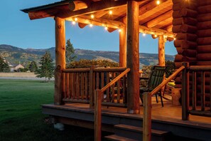 Una terraza de madera con vistas a montañas, una silla y una mesa.