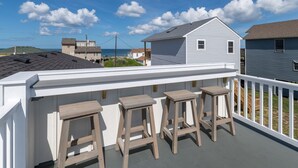 A balcony with a white railing and three wooden stools. - One More Moon 3 Bedroom Home in Kitty Hawk (Kitty Hawk)