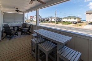 A covered outdoor area with wooden flooring, a table, and chairs. - One More Moon 3 Bedroom Home in Kitty Hawk (Kitty Hawk)