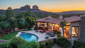 A modern house with a swimming pool, patio furniture, and a view of a mountain range.