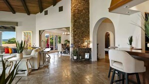 A spacious interior with a stone pillar, a fireplace, and a view through an archway.