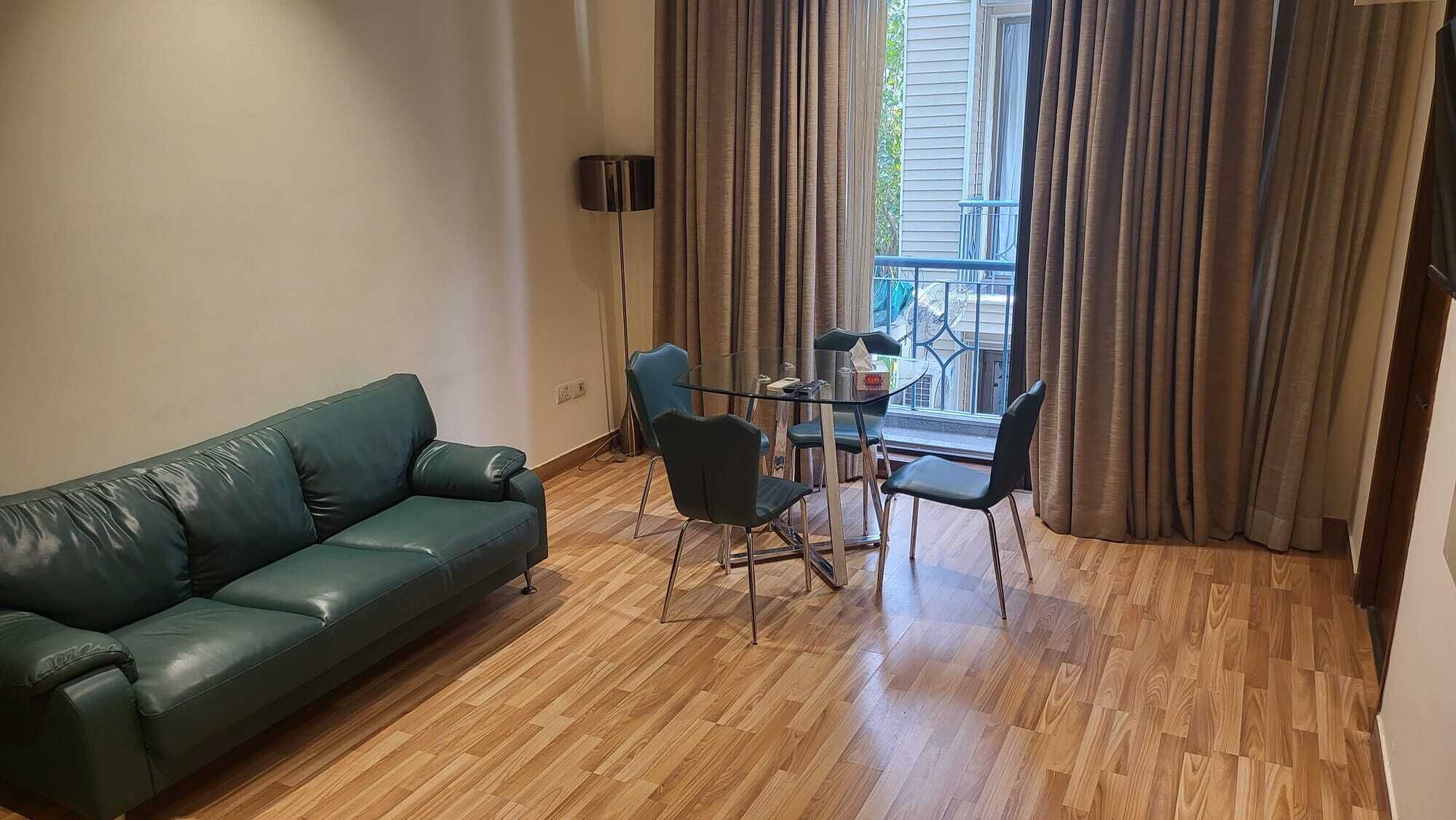 Ein Wohnzimmer mit einem grünen Ledersofa, einem Glastisch und zwei schwarzen Sesseln.