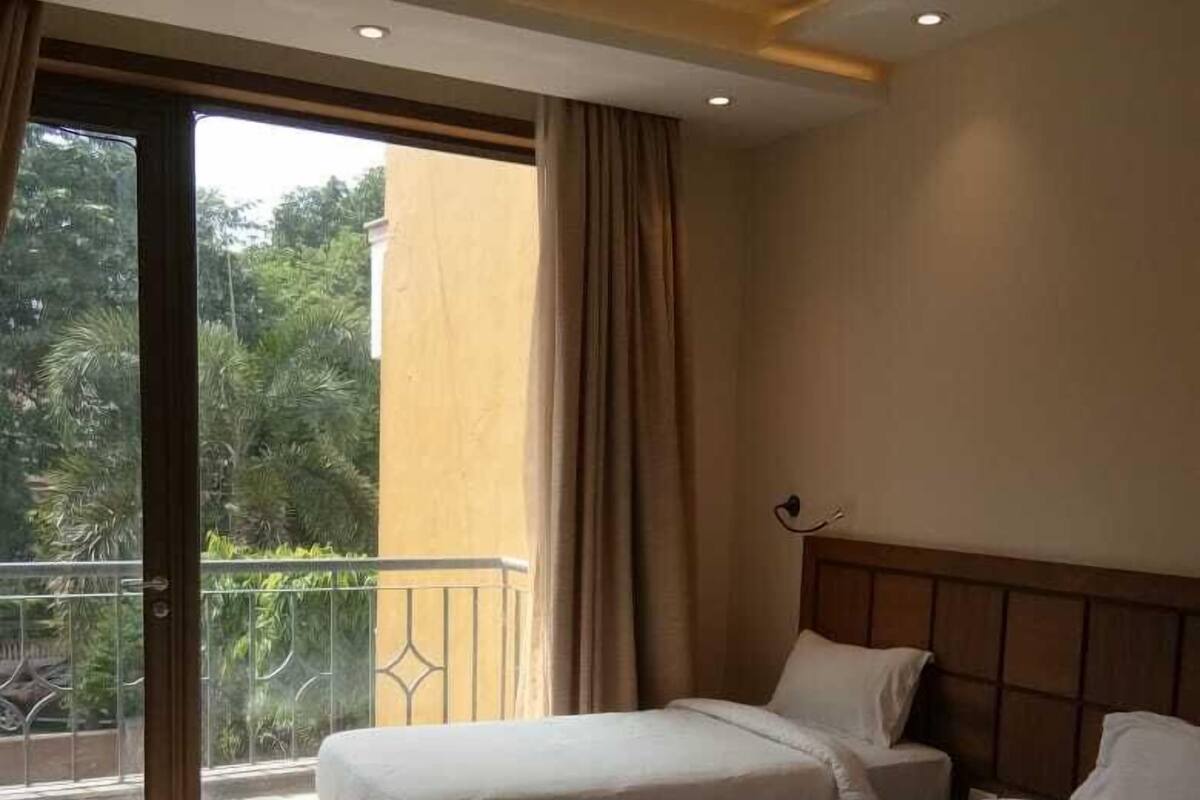 A hotel room with two beds, a sliding glass door to a balcony, and a ceiling fan.