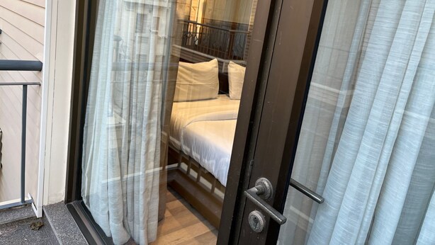 A room with a bed, a window with sheer curtains, and a door with a handle. - UDS Villa - Next to VFS, Walking to Connaught Place (New Delhi)