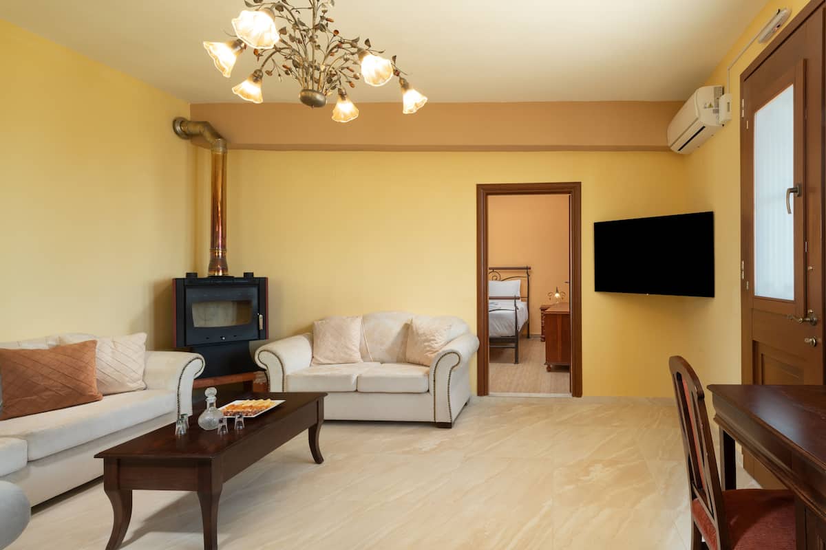 Een woonkamer met een bank, een salontafel, een open haard en een aan de muur bevestigde televisie.