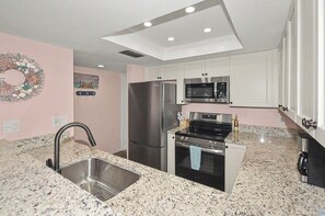 A kitchen with a stainless steel refrigerator, microwave, oven, and granite countertop.