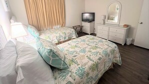 Una habitación de hotel con dos camas, un televisor, un aparador y un espejo.