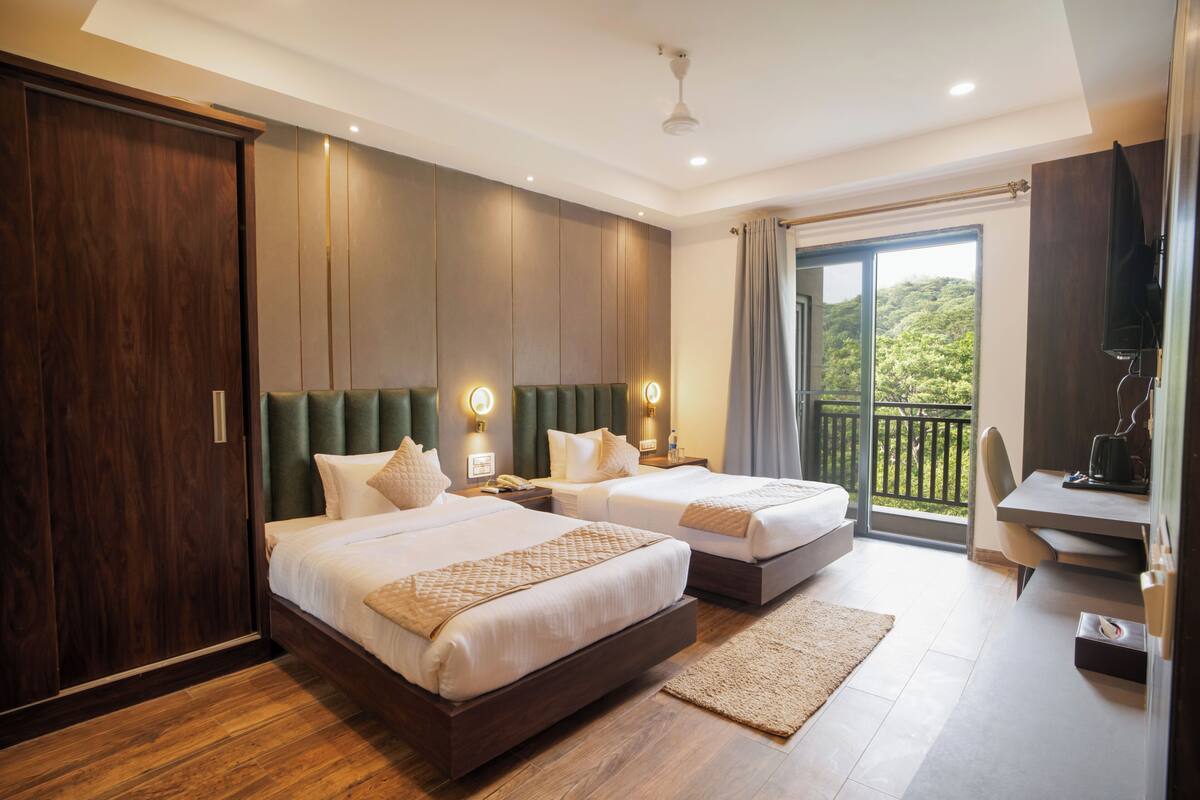 Une chambre d’hôtel avec deux lits, un bureau, une télévision et un balcon avec vue.
