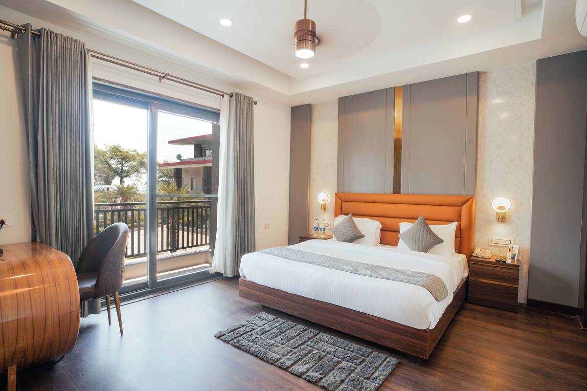 Une chambre d’hôtel moderne dotée d’un grand lit, d’un bureau, d’une chaise et d’un balcon avec vue.