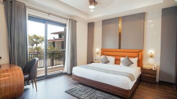 Habitación de hotel moderna con una cama grande, un escritorio, una silla y vistas al balcón.