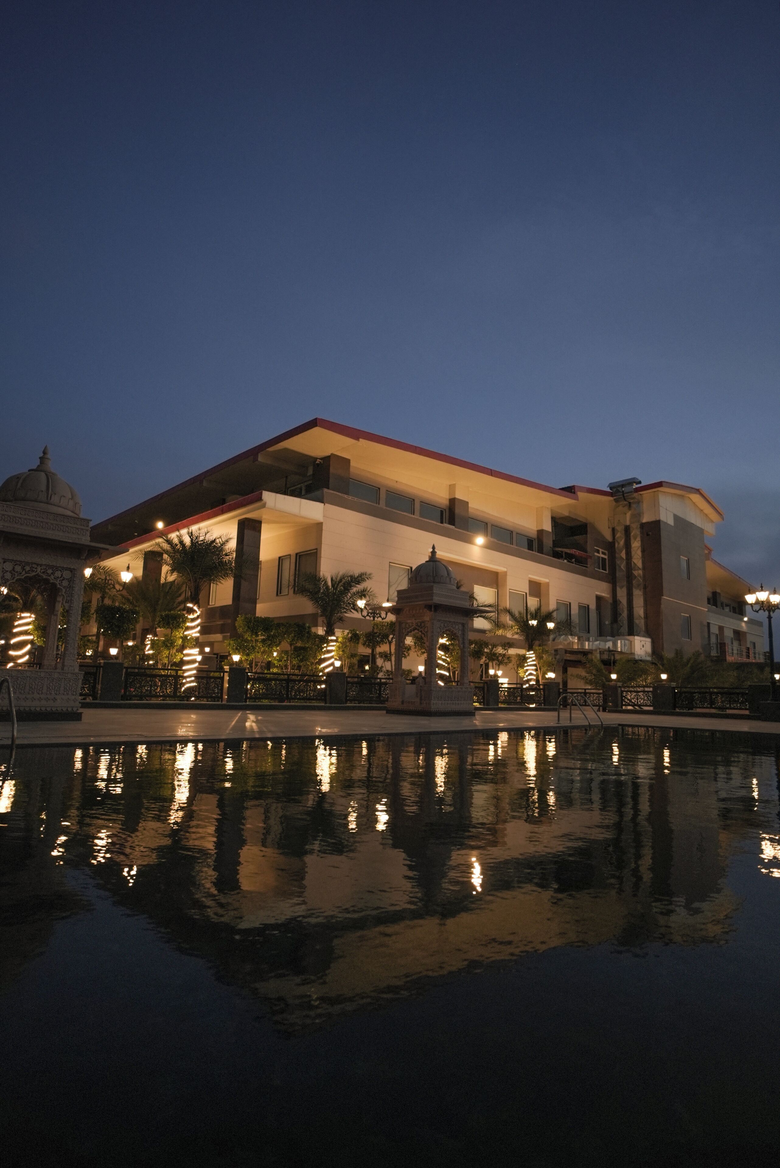 Un hotel con piscina, que refleja el edificio y las luces.