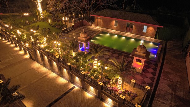 Área externa bem iluminada com piscina, um gazebo e um edifício de madeira.