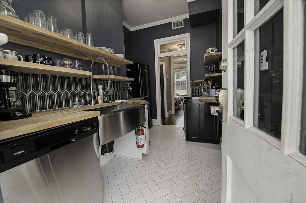 A kitchen with wooden shelves, a dishwasher, and a refrigerator.
