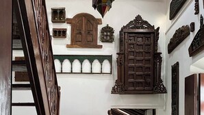 A staircase with a wooden handrail, stone steps, and a white wall with wooden doors and decorative elements. - VILLA LOU GOA Heritage Portuguese House built 1903 Exclusive Use of Private Pool (VERLA)