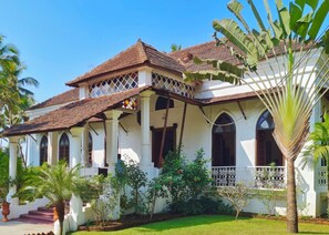 A colonial-style building with a tiled roof, arched windows, and a balcony with a lattice railing. - VILLA LOU GOA Heritage Portuguese House built 1903 with Private Pool (VERLA)
