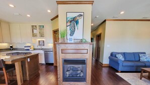 A modern kitchen with wooden flooring, a central island, and a fireplace. - Welcome to ISLAND TIME! (St. George Island)