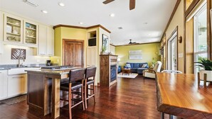 A spacious kitchen with wooden flooring, a central island with bar stools, and a dining area with a wooden table. - Welcome to ISLAND TIME! (St. George Island)