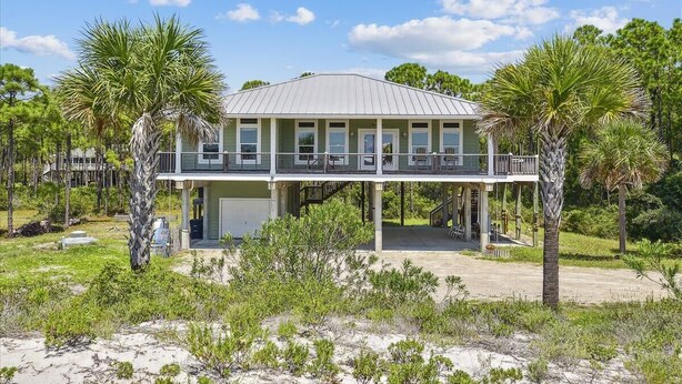 A two-story house with a balcony, surrounded by palm trees and a sandy landscape. - Welcome to ISLAND TIME! (St. George Island)