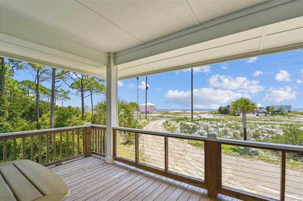 A wooden deck with a view of a coastal landscape, including trees and a road.