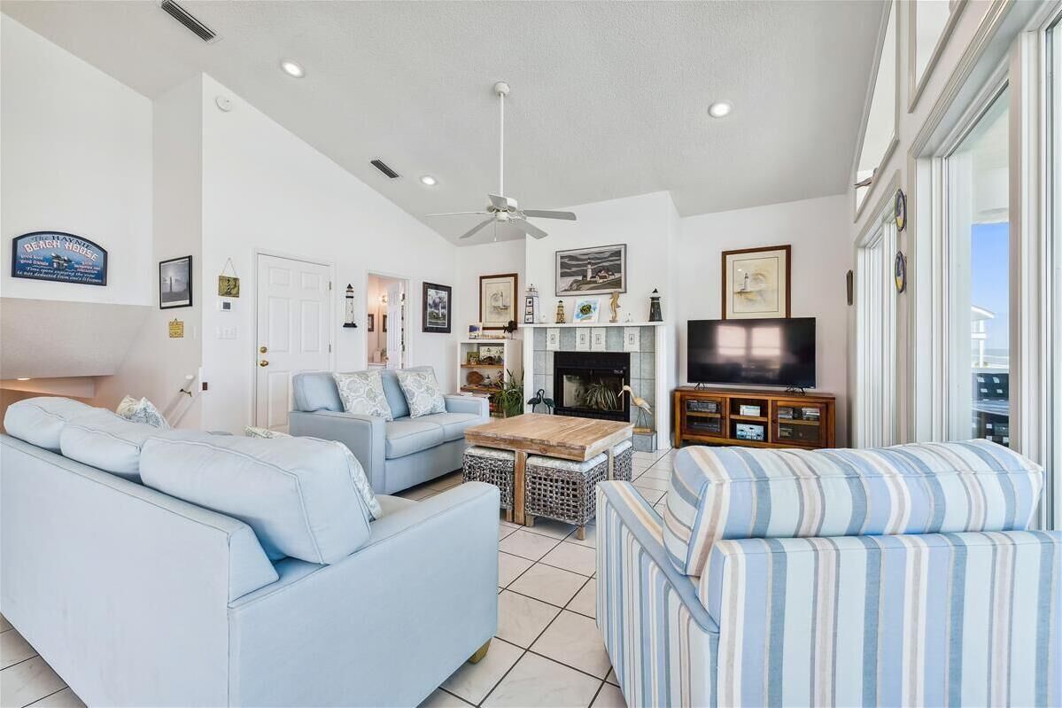 A living room with a sofa, armchairs, a coffee table, a television, and a fireplace.
