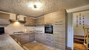Moderni keittiö, jossa on puiset kaapit, sisäänrakennettu uuni ja kaasuliesi.