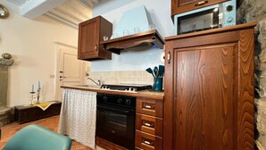 A kitchen with wooden cabinets, a stove, an oven, and a microwave.