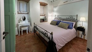 A bedroom with a bed, a vanity with a mirror, a desk, and a wardrobe.