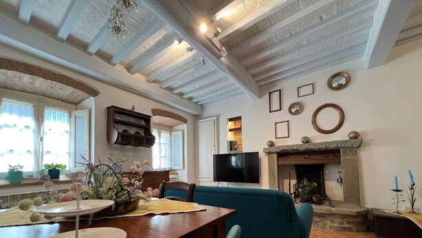A cozy living room with a fireplace, a television, and a dining area with a table and chairs.