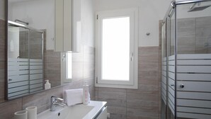 A modern bathroom with a large mirror, a sink, and a shower area. - Casa Perla by Wonderful Italy (Olbia)