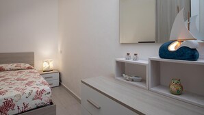 A bedroom with a bed, bedside table, nightstand, dresser, and a mirror. - Casa Perla by Wonderful Italy (Olbia)